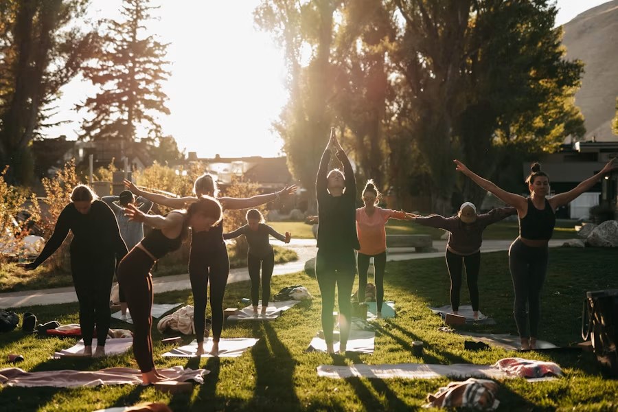 Grupo de personas practicando yoga al aire libre, en un entorno natural